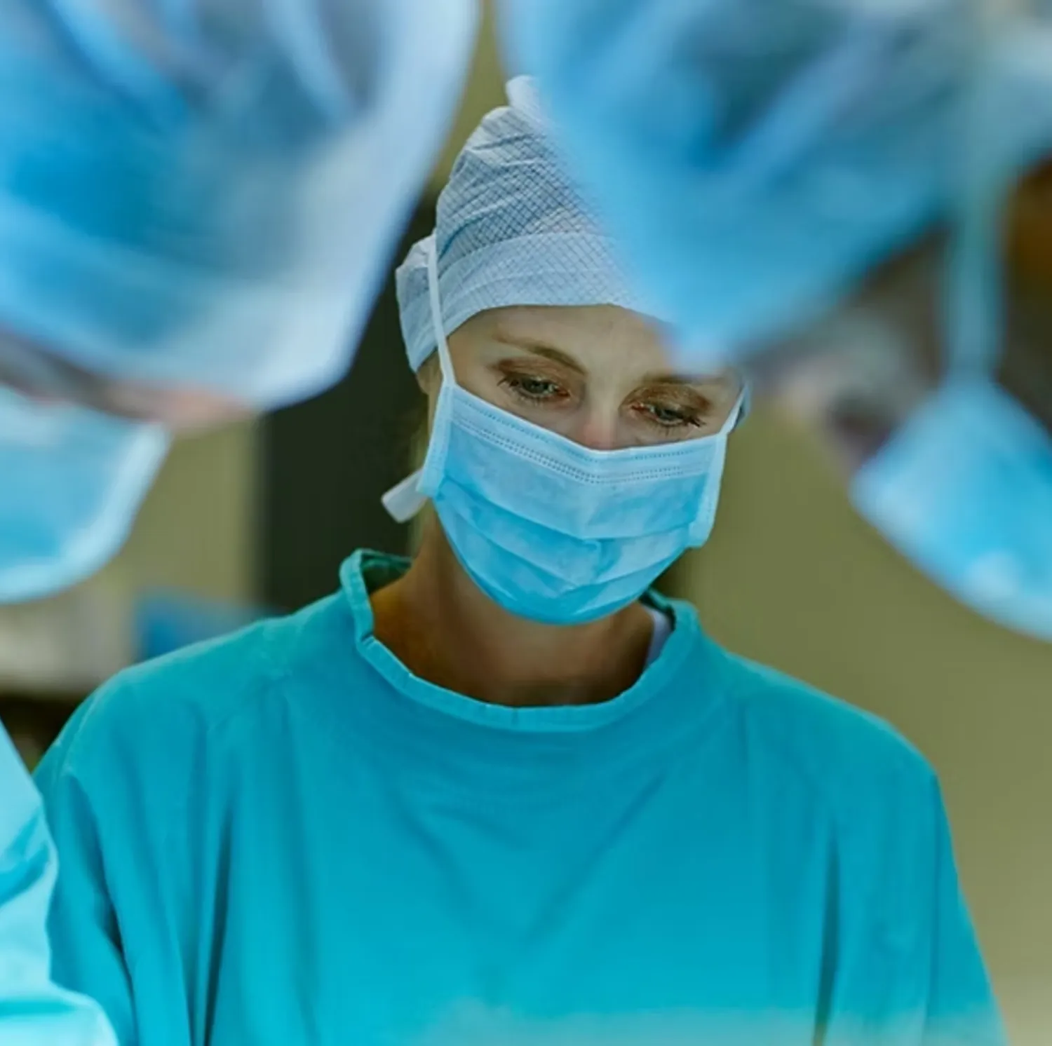 Surgeon in mask, cap and gown at work in an operating theatre
