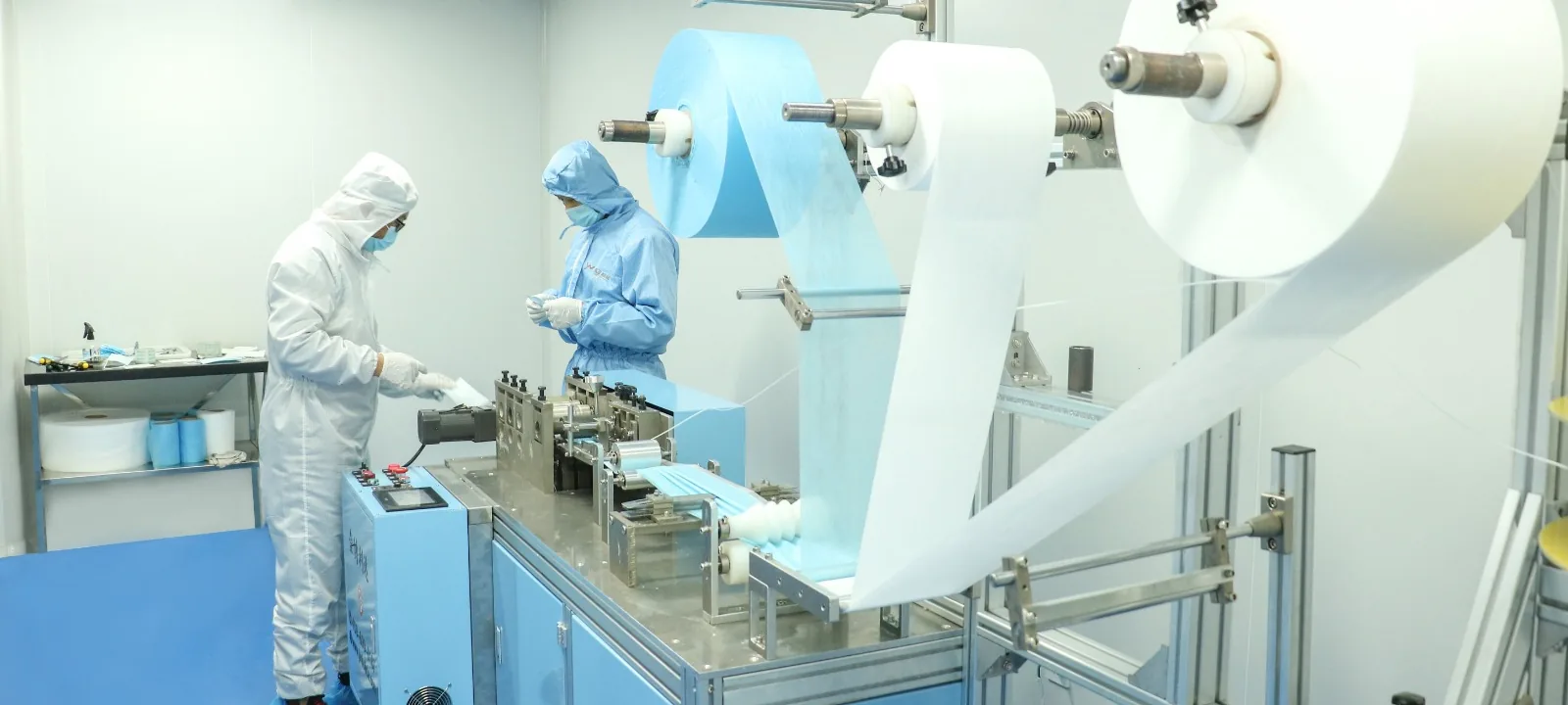 Operators in clean-room suits running a non-woven production line
